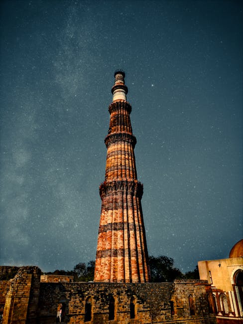 Stunning view of Qutub Minar in New Delhi under a starry night sky showcasing historical architecture.